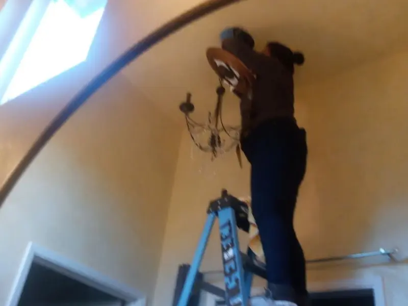 Electrician installing a chandelier in a Ames residence